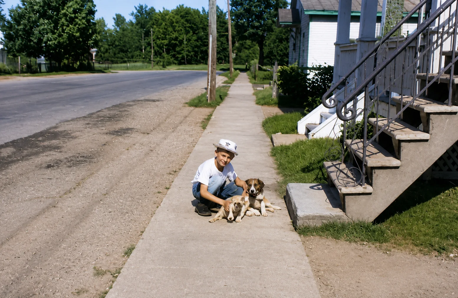 Un enfant assis avec les chiens devant la maison